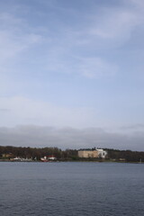 Obraz premium Panoramic view of a modern residential building by the sea on an overcast day with calm water reflection.