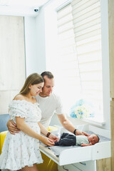 Obraz premium Newly Became Parents Cherishing Beautiful, Precious Moments with Their Newborn in a Bright, Cheerful Nursery Setting that is Filled with an Abundance of Natural Light and Joyful Atmosphere