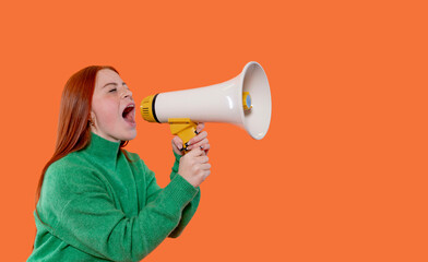 Young woman using megaphone to convey a message against vibrant orange background during an expressive moment