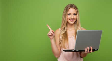 Portrait of happy young beautiful surprised woman standing with laptop isolated on green background ,  Space for text. Pointing finger.
