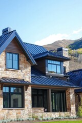 Obraz premium A contemporary stone house featuring a sleek metal roof is beautifully situated in a mountainous landscape, all under a clear blue sky during the daytime