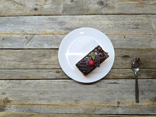 Chocolate cake with cherries lies on a white plate