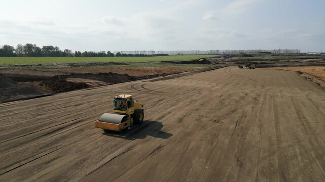 Road roller flattening ground at construction site. Clip