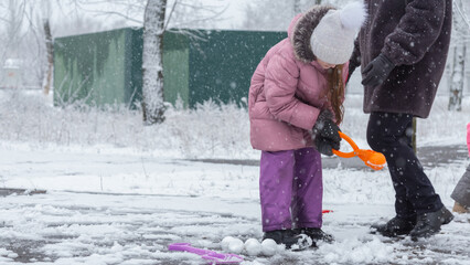 Grandmother with grandchildren in warm clothes playing outdoors in winter park, enjoying snowy...