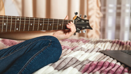 Close-up of girl's hands playing electric guitar indoors