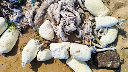 A mobile photo of a coastal composition with white textured stones, pebbles and a ship rope.