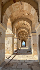 Fototapeta premium Architectural arches in a renovated corridor leading to the sea with sunlight illuminating beige stone walls, restoration concept of tourism or real estate