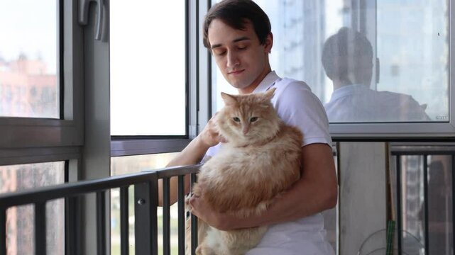 man hugging cat, petting pet on balcony. concept of friendship between man and animal. pet care