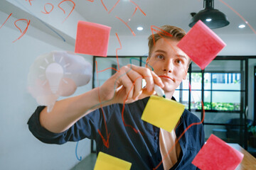 Professional caucasian businessman writing marketing idea by using mind map and sticky notes on glass board at modern meeting room. Creative business and planing concept. Closeup. Immaculate.