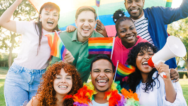 Diverse group of people celebrate gay festival in pride month party. Happy LGBT community holding rainbow flags