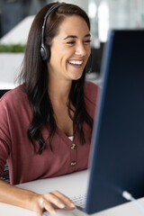 Hybrid communication. Happy laughing young woman teacher in wireless headset with microphone having...