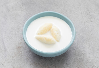 Children food. Milk soup with cottage cheese quenelles. Light gray background. Close up	