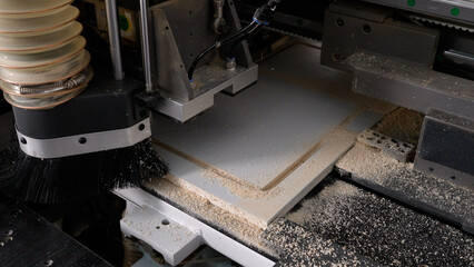 Automated cnc machine efficiently routes a wood panel, cleaning sawdust for precise woodworking