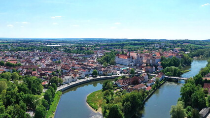 Eine beeindruckende Luftaufnahme von Neuburg an der Donau, einer malerischen Stadt in Bayern, Deutschland. Die Donau schlängelt sich durch die Stadt und bildet eine kleine Insel.