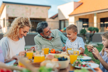Happy family enjoying lunch together in backyard