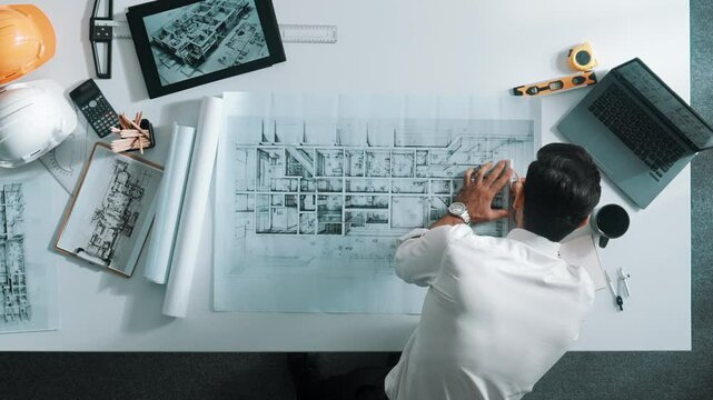 Top view of smart civil engineer drawing and measuring blueprint by using ruler. Aerial view of architect scatch building project plan at meeting table with equipment and safety helmet. Alimentation.