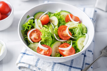 Tomato onion cucumber salad in a bowl on a white background