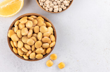 Pickled, dried lupine beans and lemon on white background. Top view. Copy space. Plant food rich in protein and fiber.