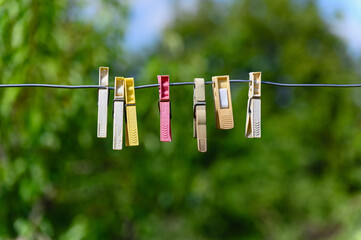 Colorful plastic clothespins hanging on wire outdoors.