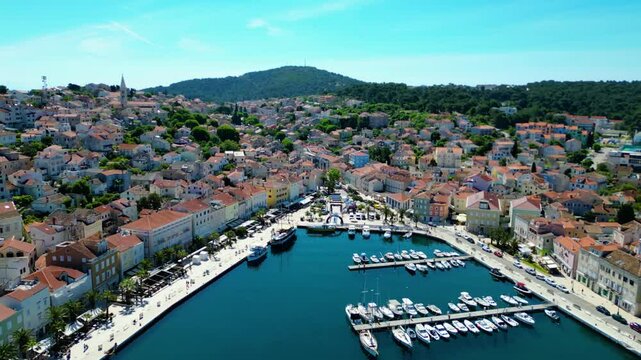 Daytime aerial view of Mali Lo&scaron;inj (Losinj), Croatia, featuring Župna crkva rođenja Blažene Djevice Marije and charming coastal architecture along the Adriatic Sea. A peaceful and sunny island scene