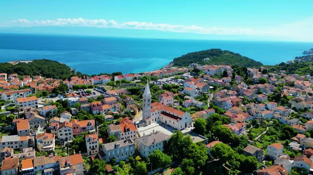 Daytime aerial view of Mali Lo&scaron;inj (Losinj), Croatia, featuring Župna crkva rođenja Blažene Djevice Marije and charming coastal architecture along the Adriatic Sea. A peaceful and sunny island scene