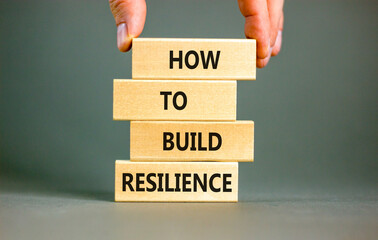 How to build resilience symbol. Concept words How to build resilience on beautiful wooden blocks. Beautiful grey background. Businessman hand. Business and how to build resilience concept. Copy space.