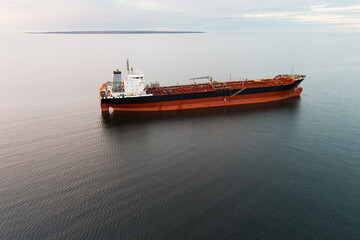 Fototapeta premium Large oil tanker in the open sea: aerial shot of a cargo vessel on calm water under an overcast sky.
