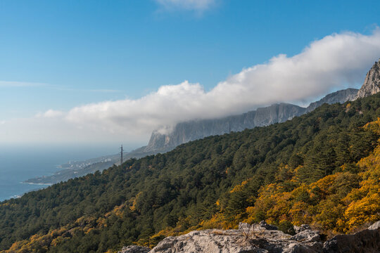 Mountains Crimea Coastline Autumn: Panoramic view showcasing Crimean mountains, coastal scenery, autumn foliage. Low clouds partially obscure distant sea.