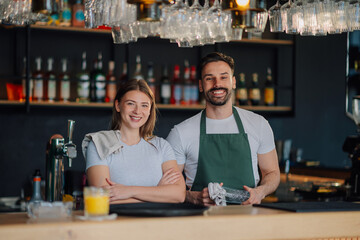 Bartenders smiling behind the counter of their successful bar
