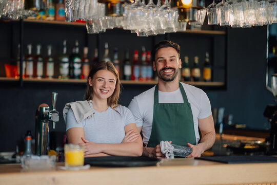 Bartenders smiling behind the counter of their successful bar