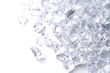 Close-up of scattered clear ice cubes shining in bright light on a white background, perfect for beverage presentation