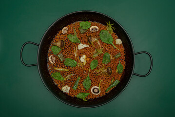 A typical paella pan with lettuce and rice cooked on a smooth green surface