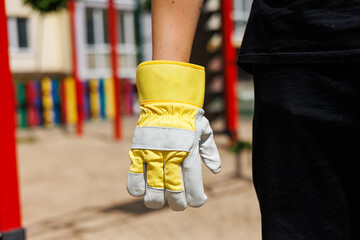 The protective work glove is currently hanging in a vibrant playground environment, highlighting...