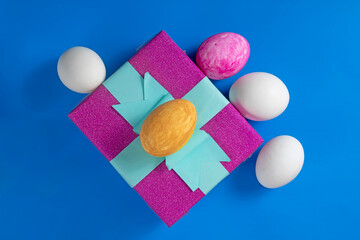 Colorful Easter eggs with gift box on bright blue background.