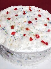A fluffy lemon coconut cake topped with shredded coconut, glazed cherries, and colorful sugar sprinkles—perfect for celebrations and tropical dessert lovers.