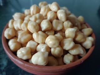 Freshly soaked white chickpeas in a terracotta bowl. High-protein legume used in Indian cooking, salads, and healthy recipes.