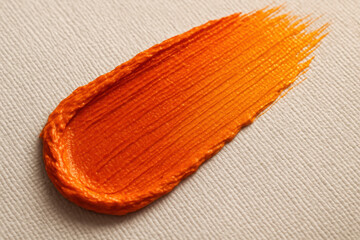 Orange Paint Stroke on Canvas: A close-up showcases an expressive and vibrant smear of orange paint, artfully applied upon a textured canvas surface.