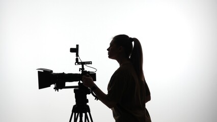 Naklejka premium Silhouette of Woman Operating Professional Video Camera on Set