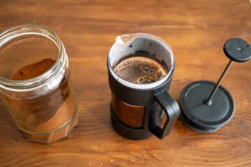 Brewing and pouring coffee with black french press on table in close-up
