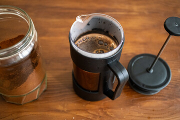 Brewing and pouring coffee with black french press on table in close-up