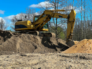 A large backhoe loader standing on a pile of earth