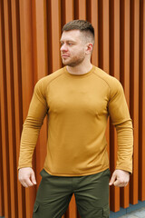 In this striking photo, a stylish man in a bold mustard long sleeve shirt poses confidently against...