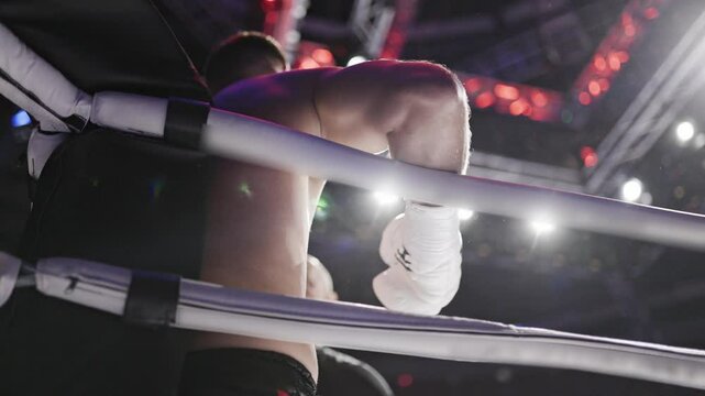 Boxer leaning on boxing ring ropes in slow motion