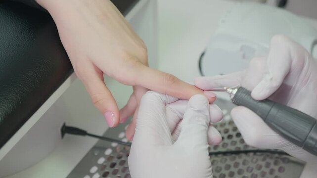Hardware Manicure process in a beauty salon close up. Professional manicurist in gloves cut the cuticle with a electric file. Concept nails and hands care 