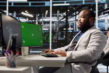 Data center technician inspecting gear using green screen mockup PC, doing maintenance tasks....