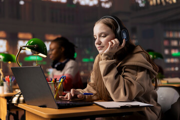 College scholar paying attention during online class webinar via video conferencing, takes notes...