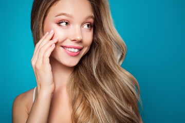 Young woman with natural beauty and perfect blonde hair smiling against a vibrant blue background