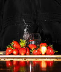 Strawberries Splashing in Water with Reflection on Black Background