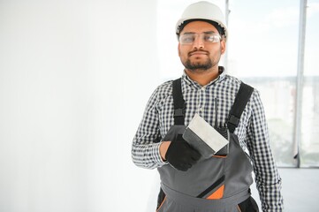 Indian Worker spreading plaster to wall with trowel, repairing works