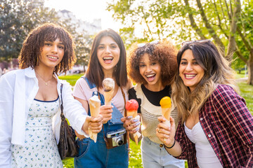Four cheerful multi ethnic women eating ice cream in a park